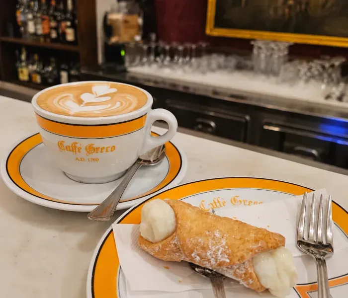Cappuccino e cannoli no balcão do Caffè Greco, em Roma